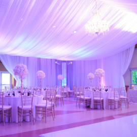 a purple lit formal dining space with draped fabric along the ceiling. 